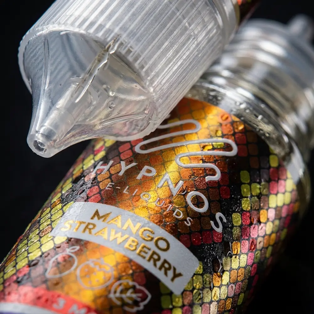 Close-up do rótulo Hypnos Mango Strawberry mostrando tipografia, textura do rótulo, bico e gotas realistas - Vapor Gringo