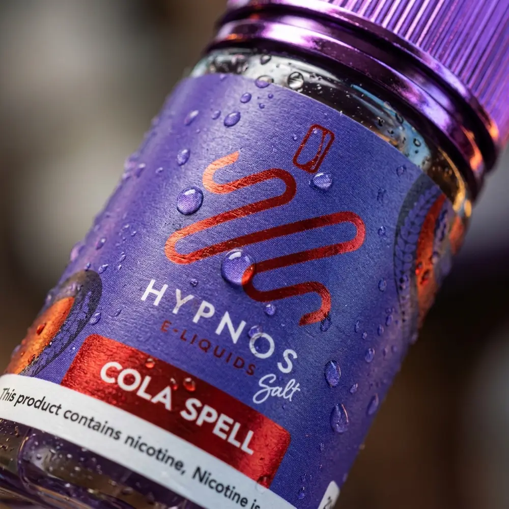 Close-up do rótulo e gotículas no frasco Hypnos Salt Cola Spell mostrando textura e brilho - Vapor Gringo
