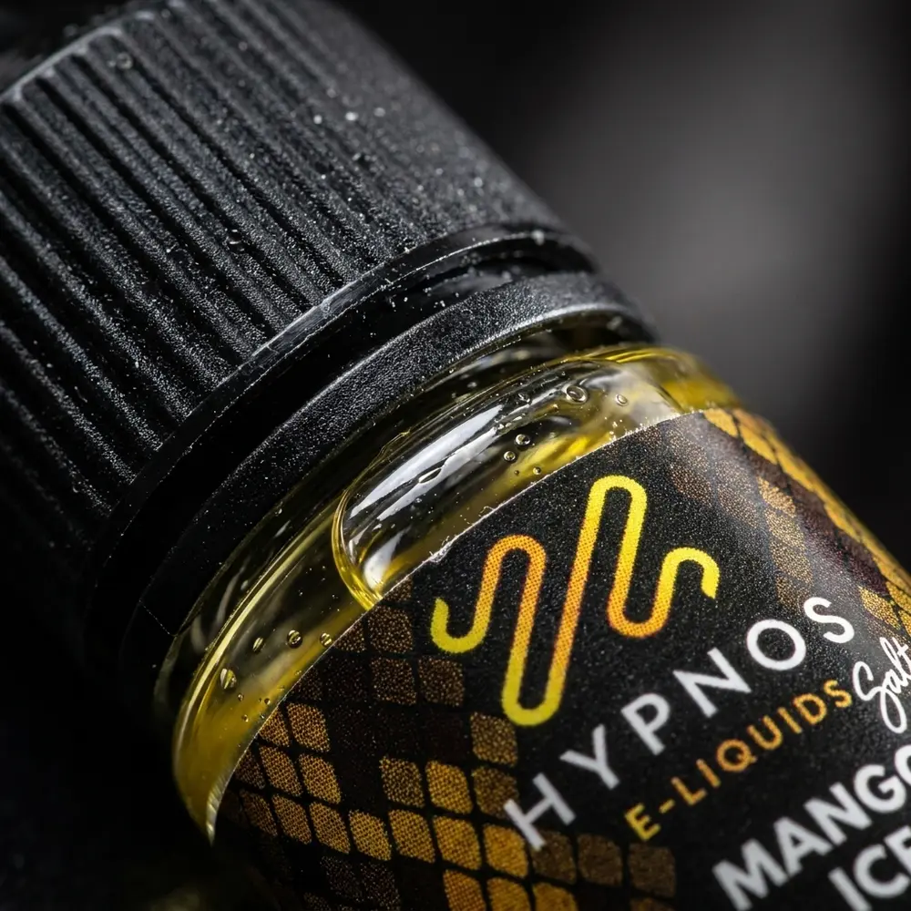Close-up do rótulo e bico do Hypnos Salt Mango Ice com gotas de condensação e reflexos metálicos no vidro - Vapor Gringo