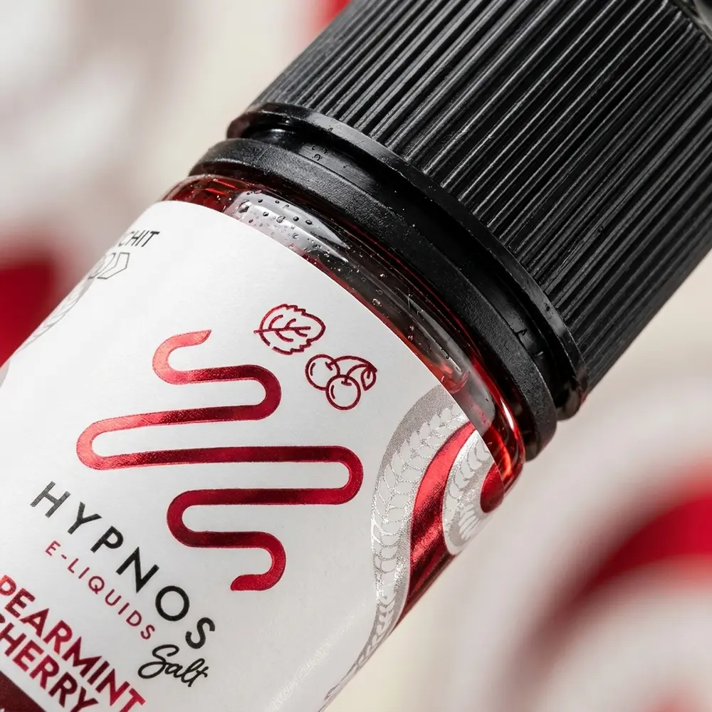 Close-up do bocal e rótulo do Hypnos Salt Spearmint Cherry, gotas de condensação e textura do plástico - Vapor Gringo