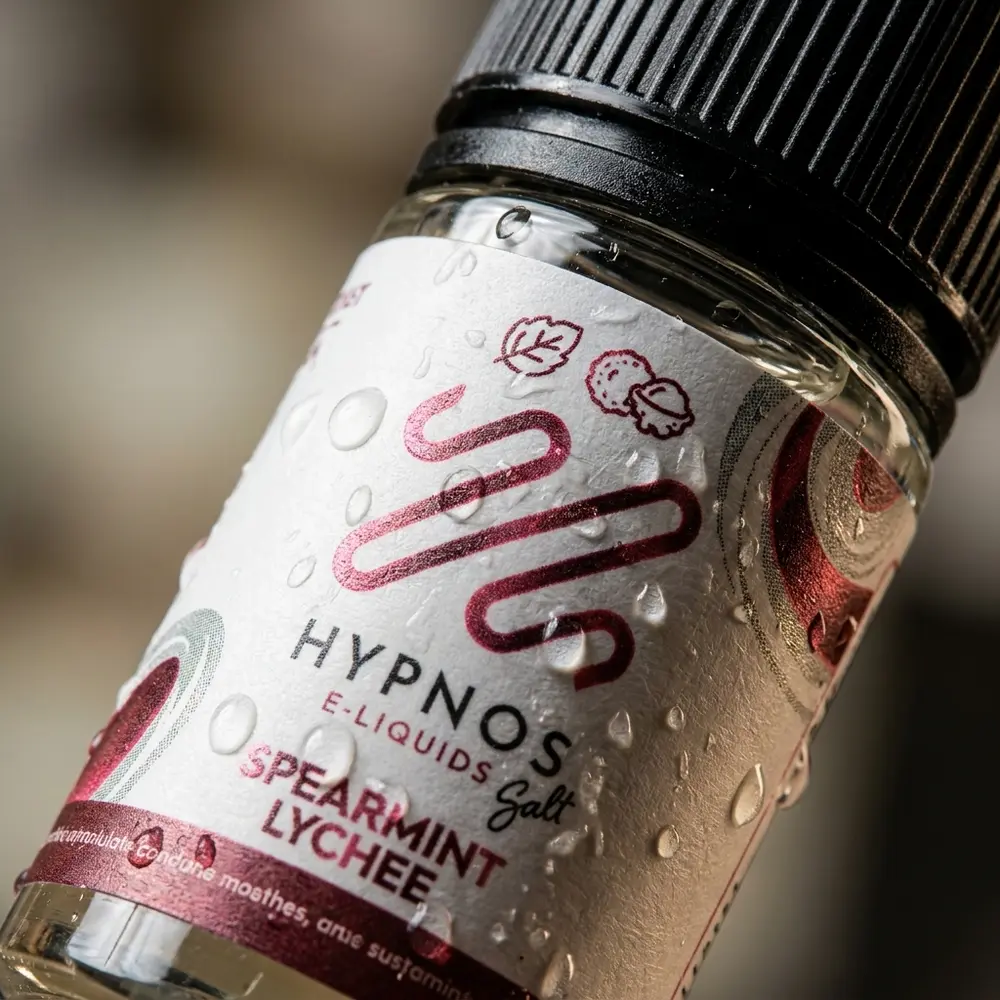 Close-up do rótulo e bico do Hypnos Salt Spearmint Lychee 30ml, gotas, textura da etiqueta e reflexos - Vapor Gringo