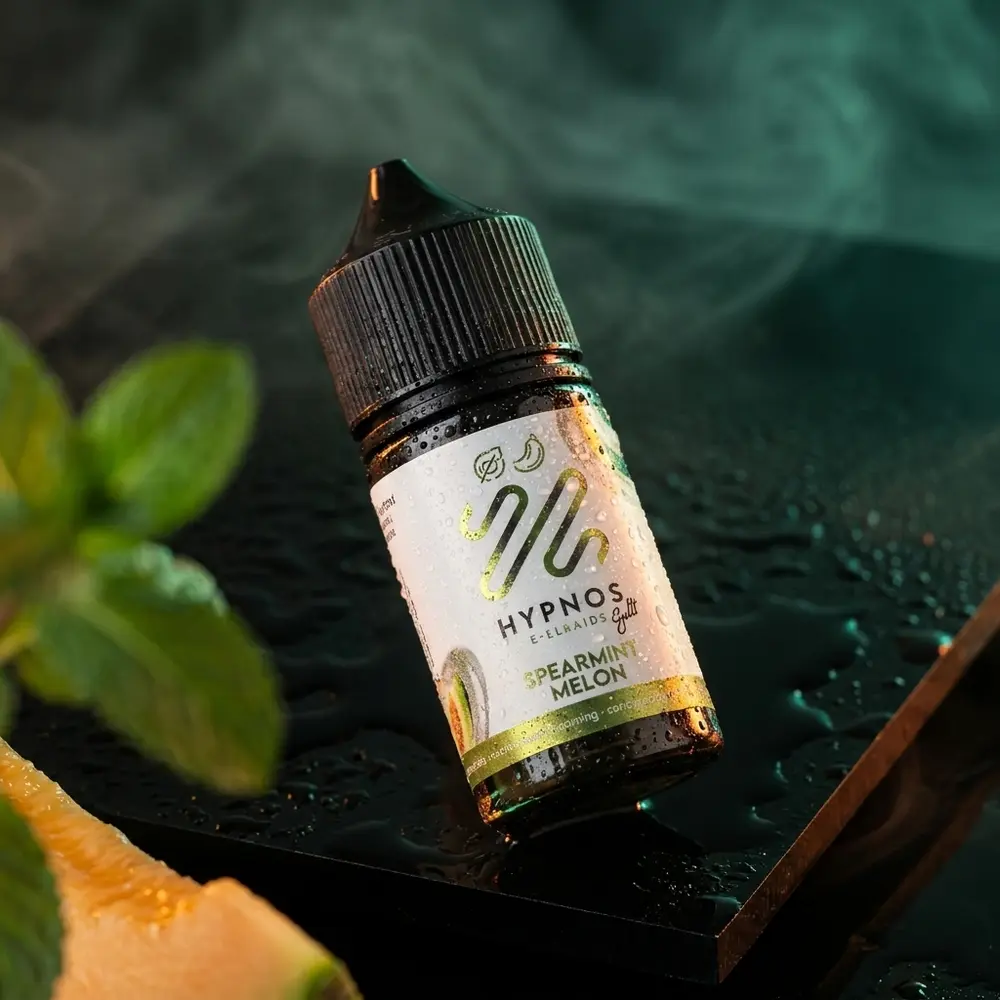 Garrafa do liquido Hypnos Salt Spearmint Melon sobre acrilico preto com gotas e luzes verdes e laranja - Vapor Gringo