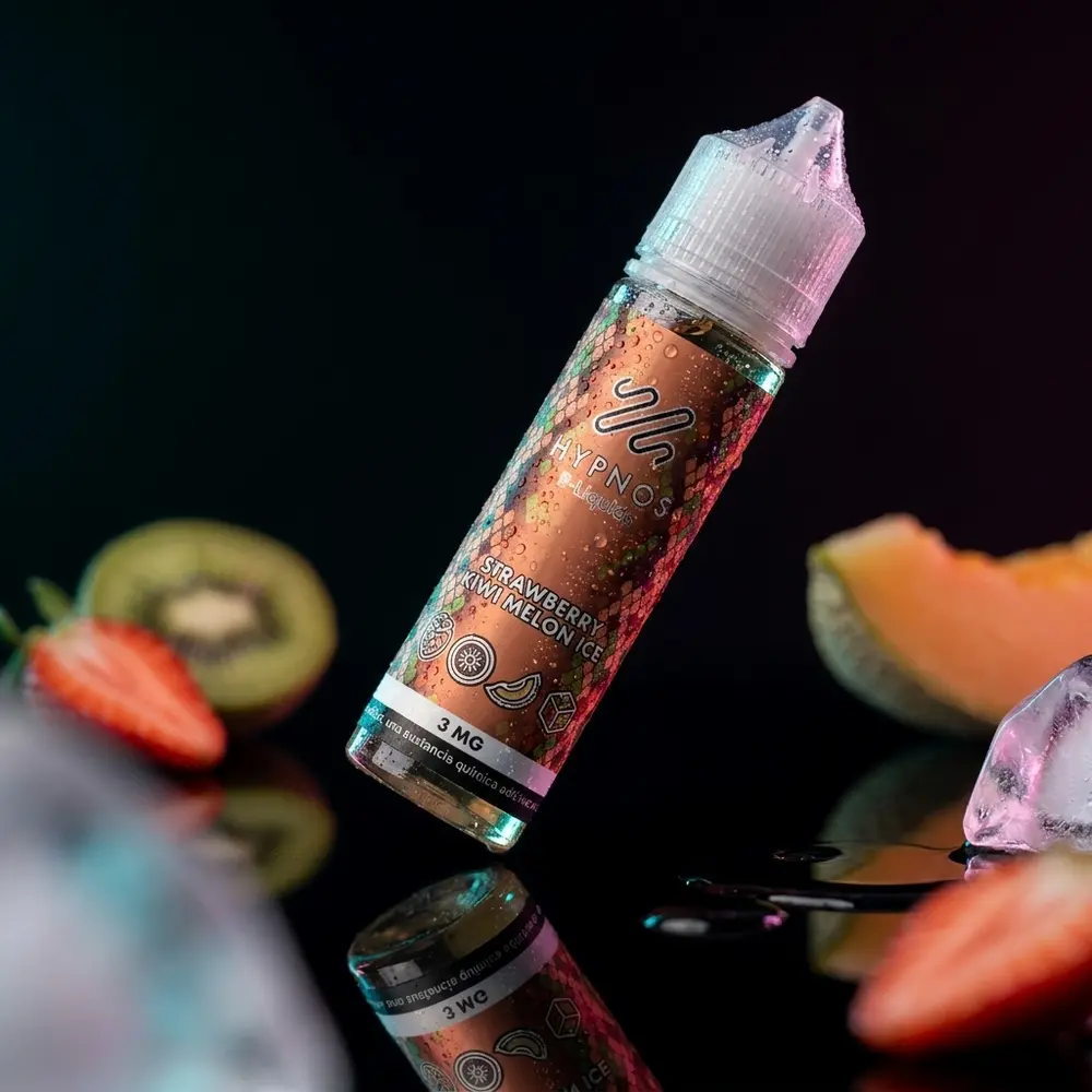 Garrafa Hypnos Strawberry Kiwi Melon Ice inclinada sobre base preta refletiva, condensacao e frutas geladas ao redor - Vapor Gringo