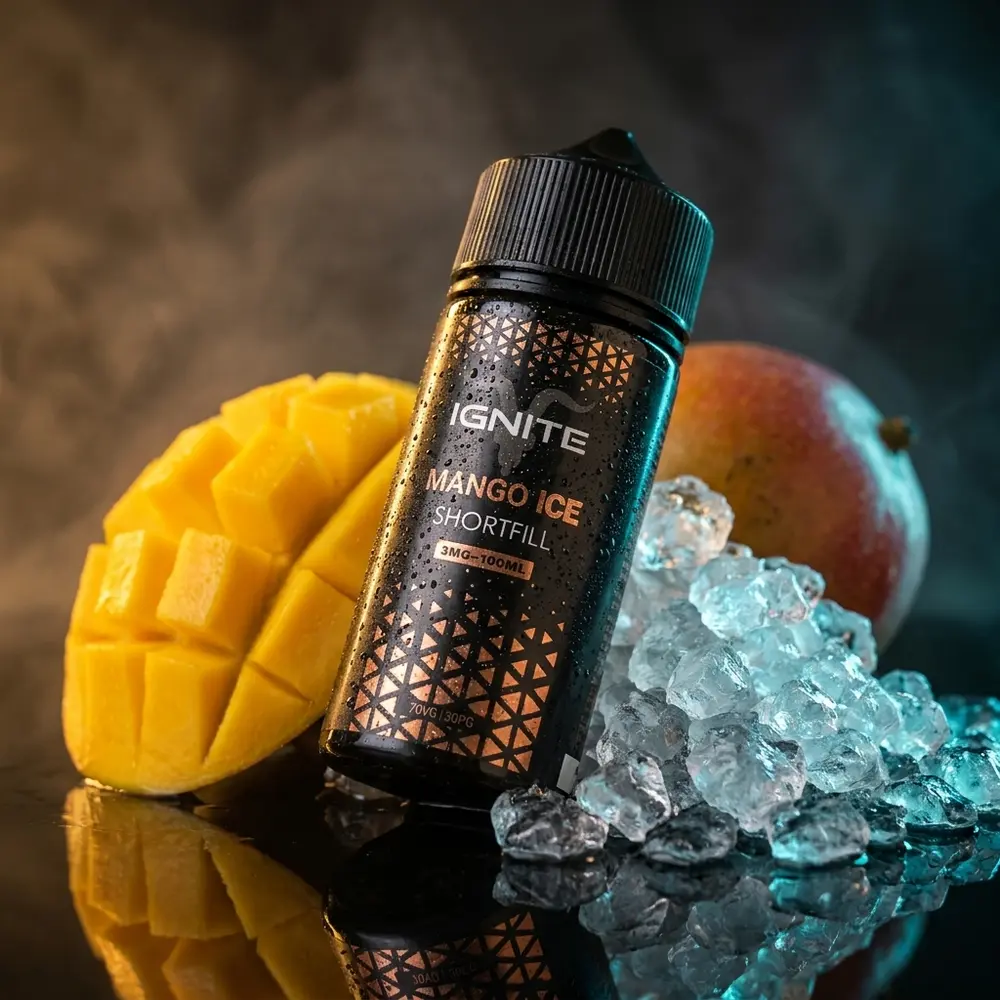 Líquido Ignite Mango Ice: frasco com rótulo intacto sobre acrílico preto molhado, fatias de manga e gelo ao redor - Vapor Gringo