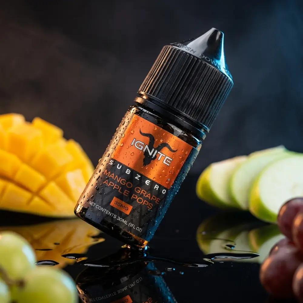 Garrafa Líquido Ignite Salt SubZero Mango Grape Apple Pops em close sobre acrílico preto com gotas. - Vapor Gringo