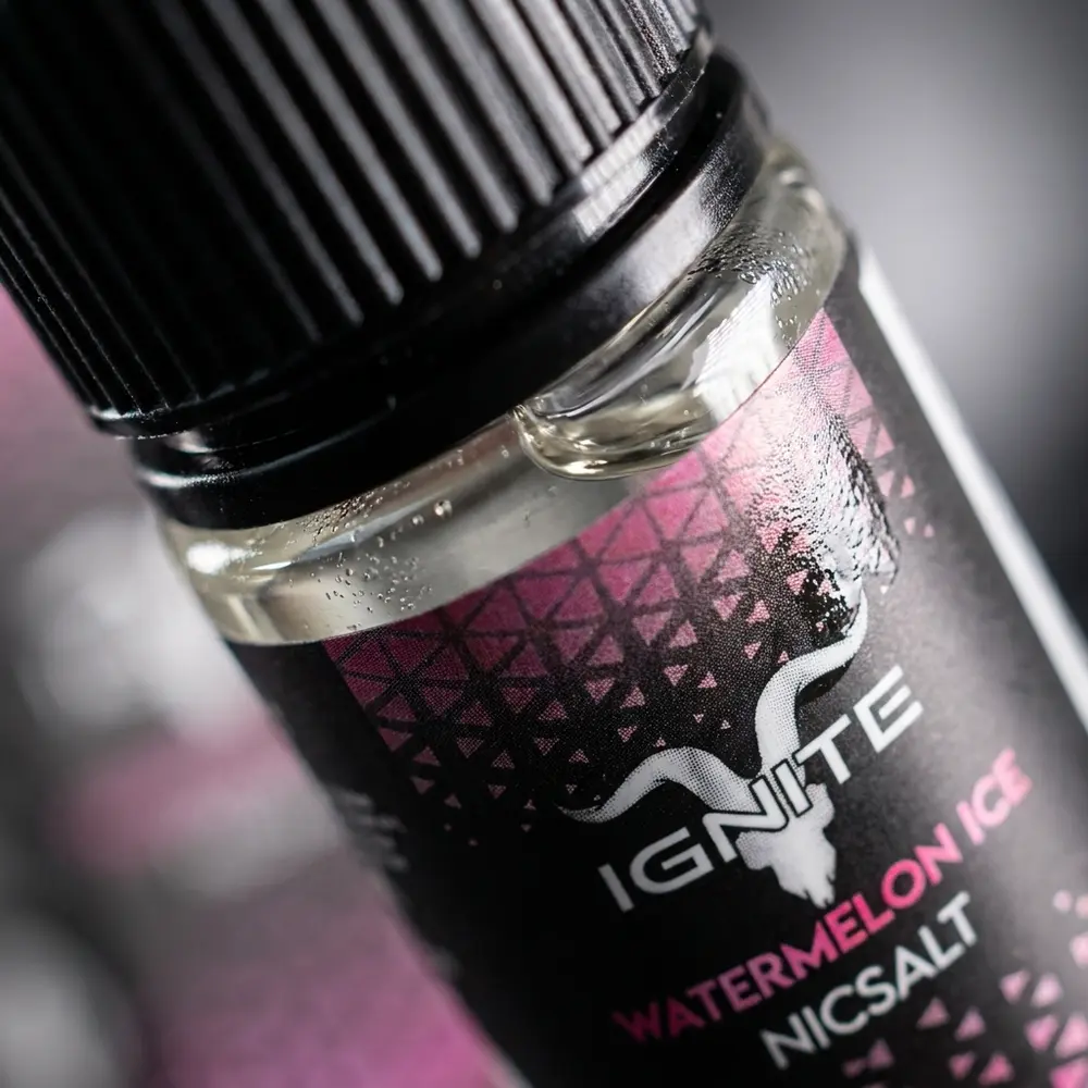 Detalhe macro do rótulo do Líquido Ignite Salt - Watermelon Ice com gotas de condensação e reflexos metálicos - Vapor Gringo