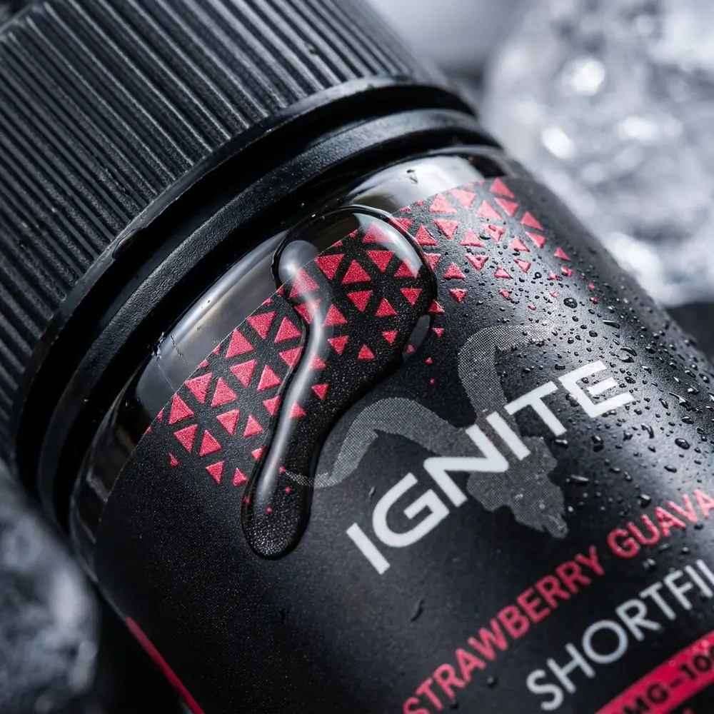 Close do rótulo do liquido Ignite Strawberry Guava Ice com gotas de condensação e reflexos metálicos - Vapor Gringo