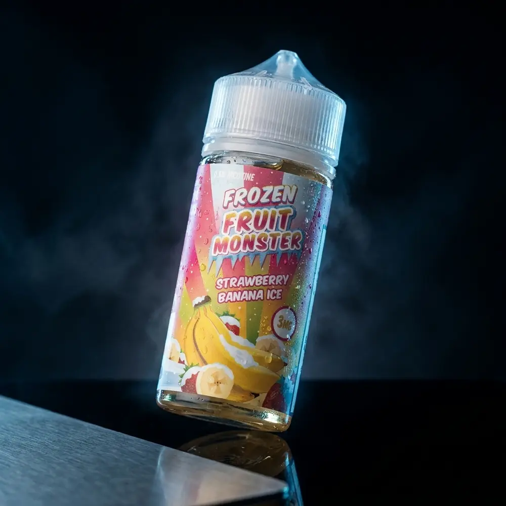 Garrafa de líquido Jam Monster Strawberry Banana Ice sobre base acrílica preta, iluminação azul fria e reflexos metálicos com condensação. - Vapor Gringo