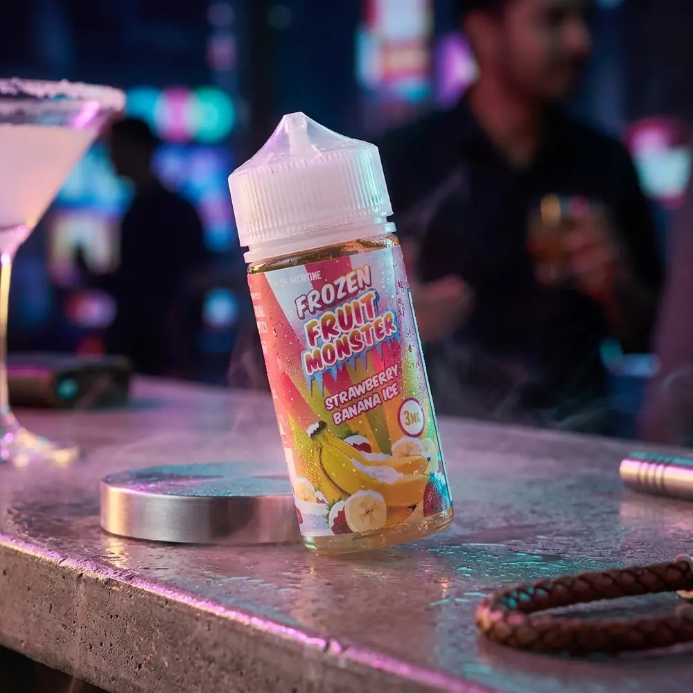 Líquido Jam Monster Strawberry Banana Ice apoiado em balcão urbano com reflexos neon RGB e ambiente noturno desfocado. - Vapor Gringo