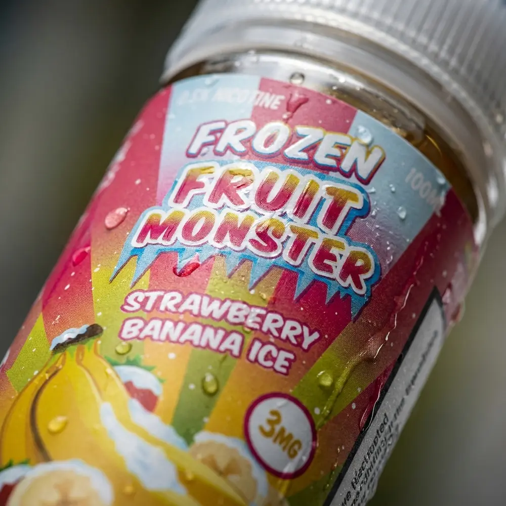 Close-up do rótulo e bocal do Jam Monster Strawberry Banana Ice com gotas de condensação e texturas do rótulo visíveis. - Vapor Gringo
