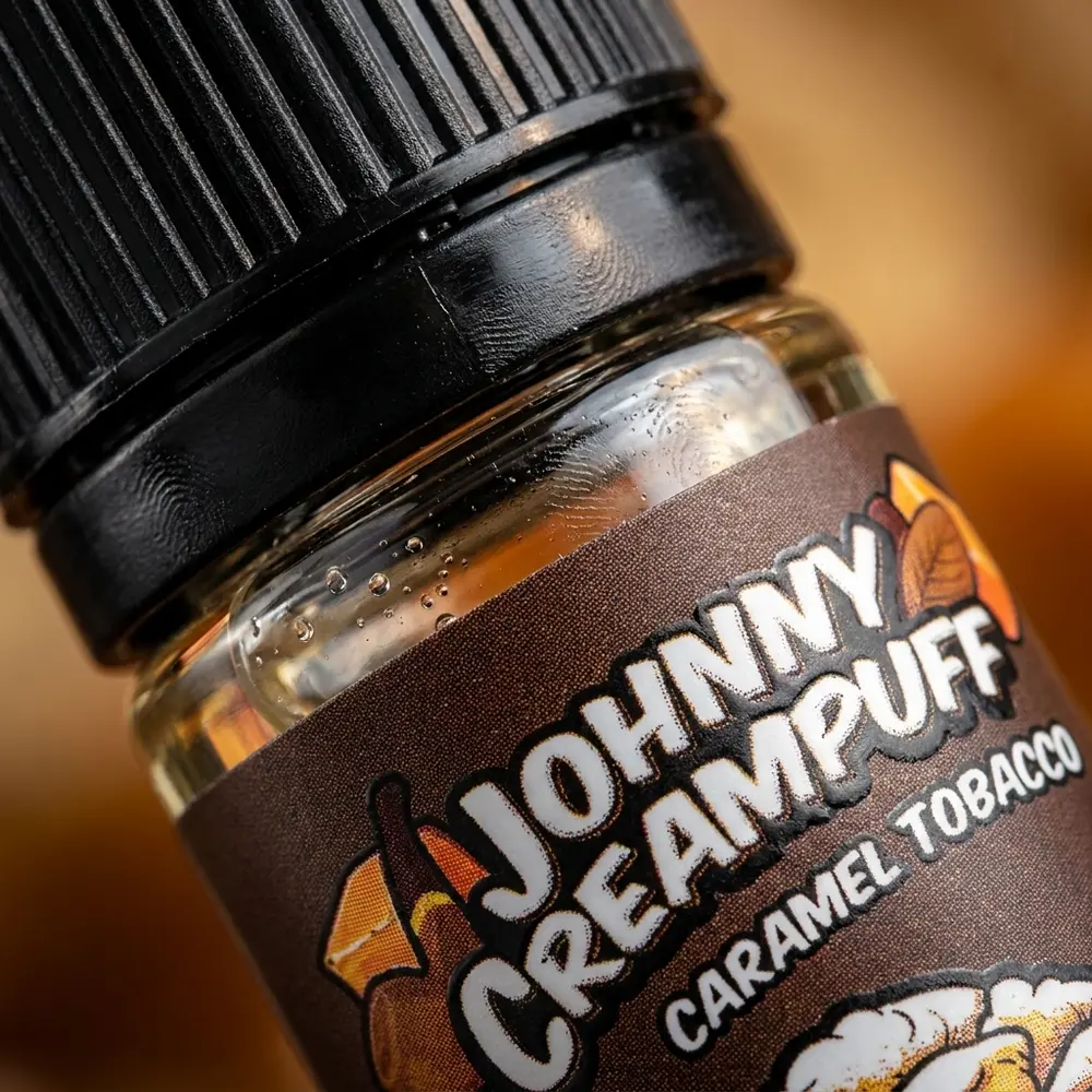 Close-up da tampa e rótulo do Johnny Creampuff Salt com gotas de condensacao e reflexos de caramelo - Vapor Gringo
