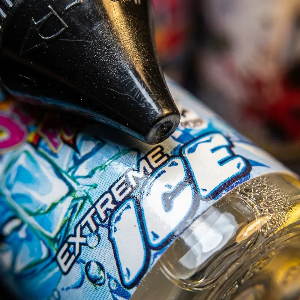 Close-up do rótulo Liquido Juice Ploos Pineapple com gotas, textura do vidro e reflexos detalhados - Vapor Gringo