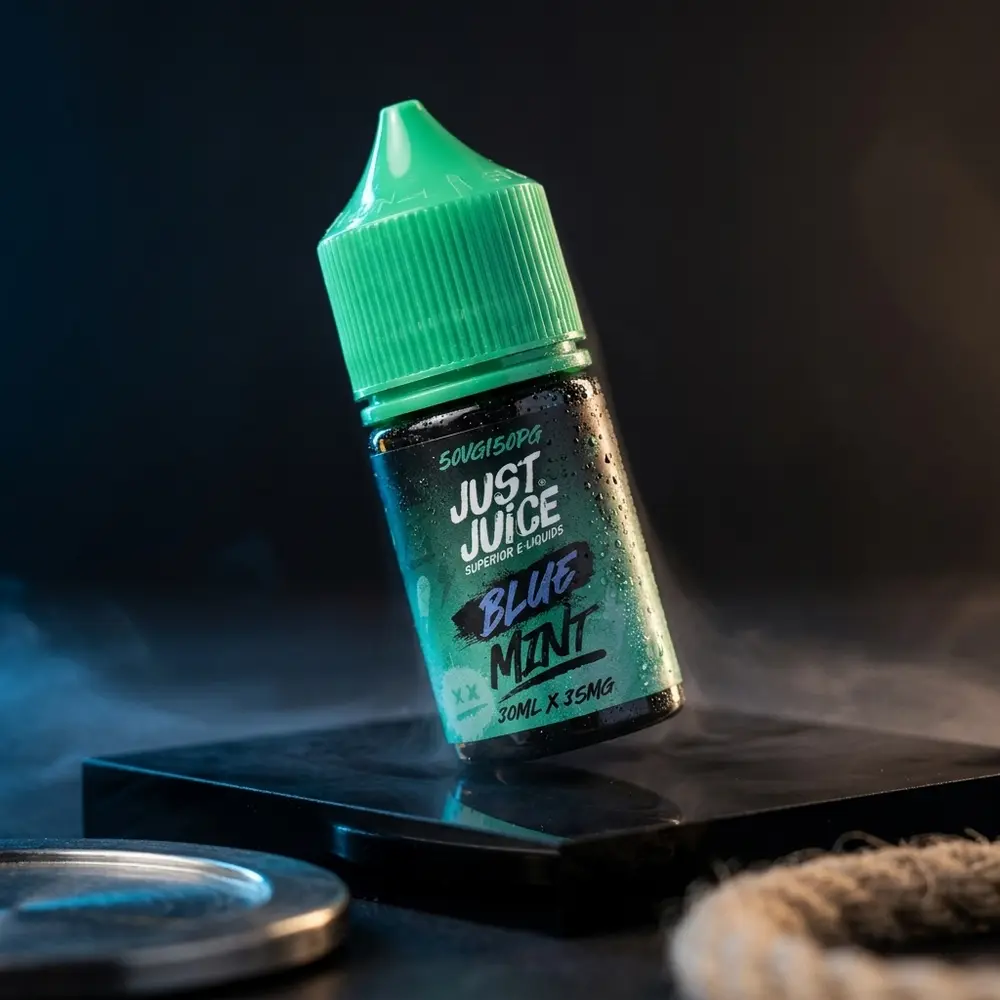 Garrafa de 30ml Líquido Just Juice Salt Blue Mint sobre base acrílica molhada, iluminação fria e reflexos premium - Vapor Gringo