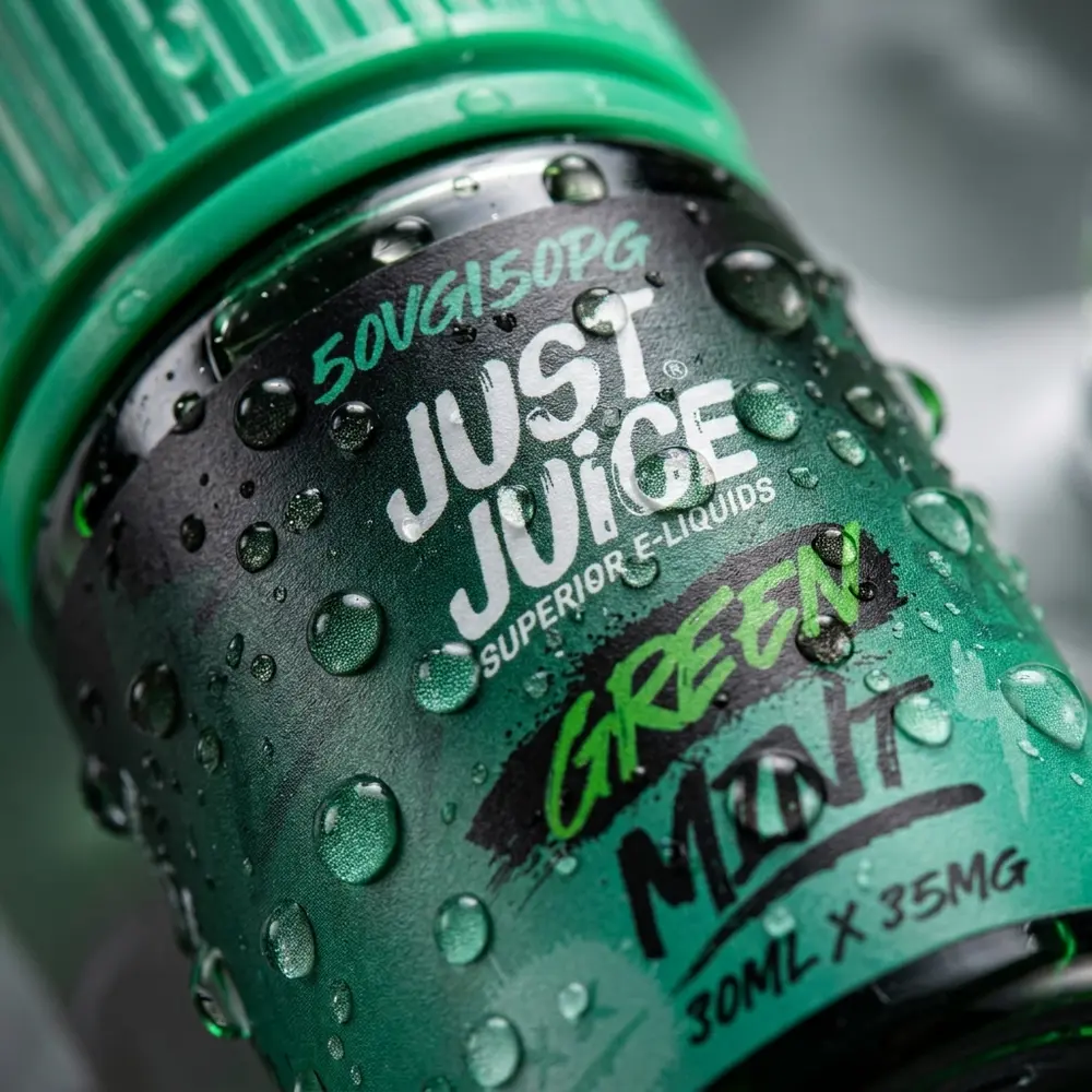 Close-up do rótulo e bocal da Just Juice Salt Green Mint com gotas e reflexos verdes - Vapor Gringo