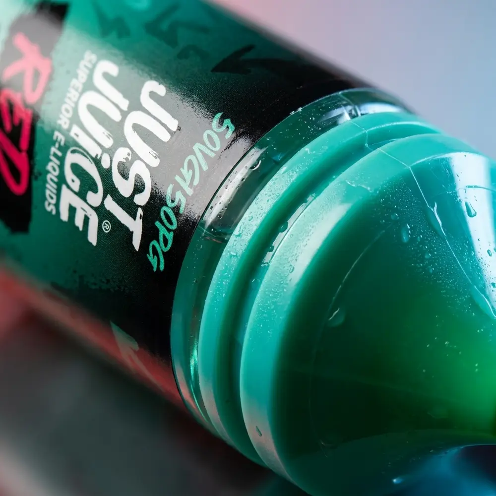 Close-up do rótulo e bico do Líquido Just Juice Salt Red Mint com gotas e reflexos detalhados - Vapor Gringo