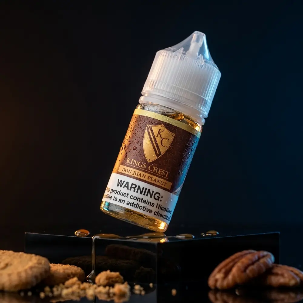 Frasco Kings Crest Don Juan Peanut em pedestal acrilico com gotas, luzes quentes e elementos de sobremesa - Vapor Gringo