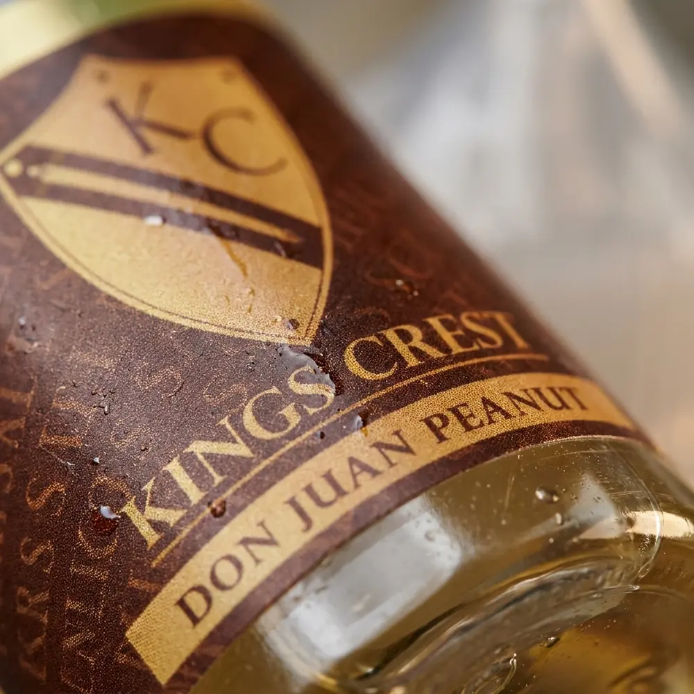 Close macro do rotulo e bico do Kings Crest Don Juan Peanut com condensacao e reflexos metalicos - Vapor Gringo