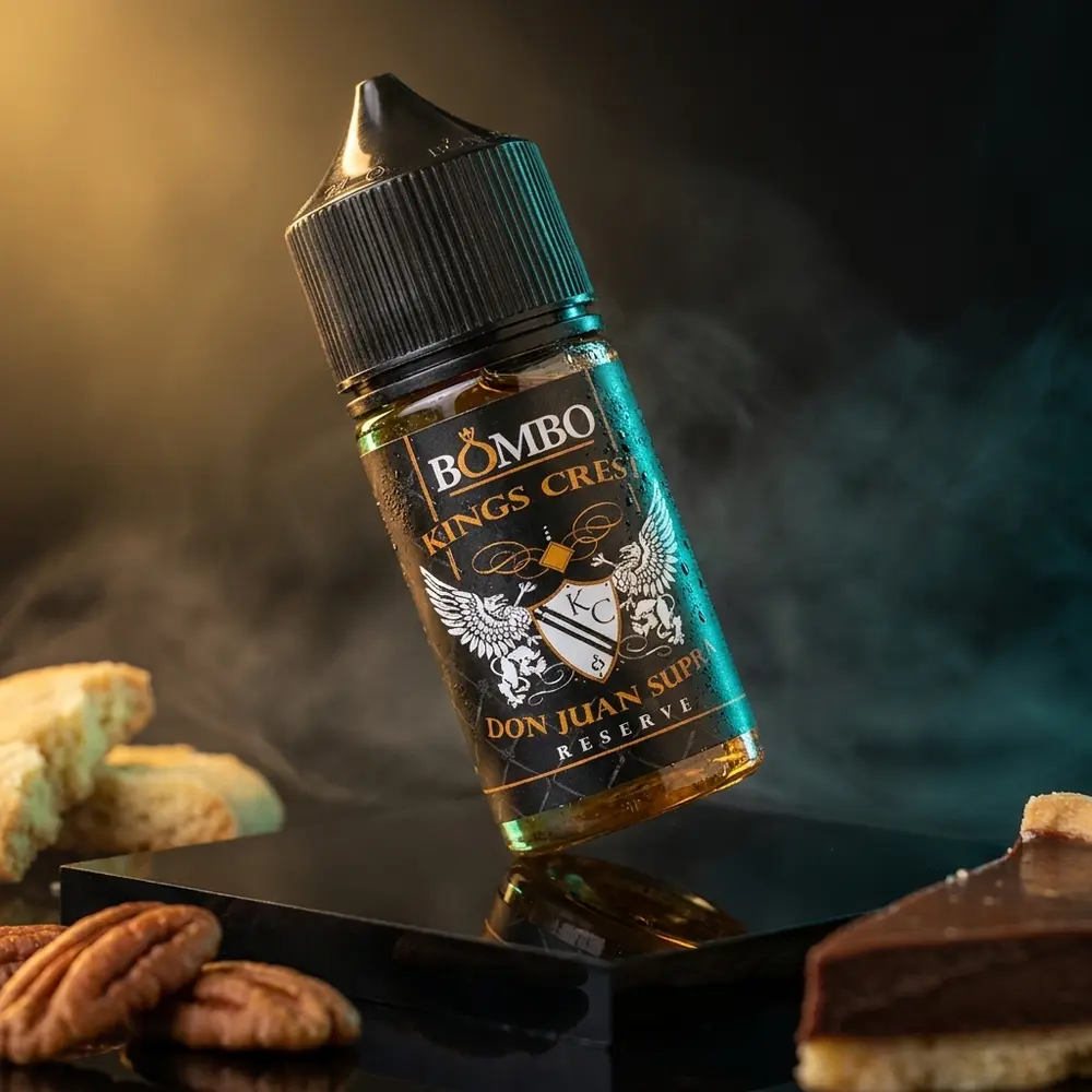 Garrafa Liquido Kings Crest Don Juan Supra 30ml sobre acrilico preto com gotas, nozes pecan e pedaço de torta. - Vapor Gringo