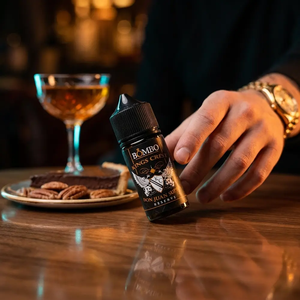 Garrafa Liquido Kings Crest Don Juan Supra 30ml em lounge de luxo sobre mesa com cocktail e nozes pecan ao fundo. - Vapor Gringo
