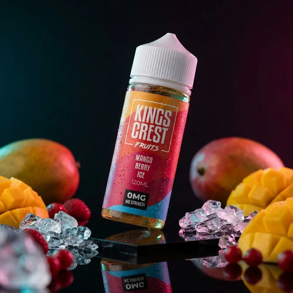 Líquido Kings Crest Mango Berry Ice 120ml em cena de estúdio, garrafa inclinada sobre acrílico com gelo e frutas - Vapor Gringo