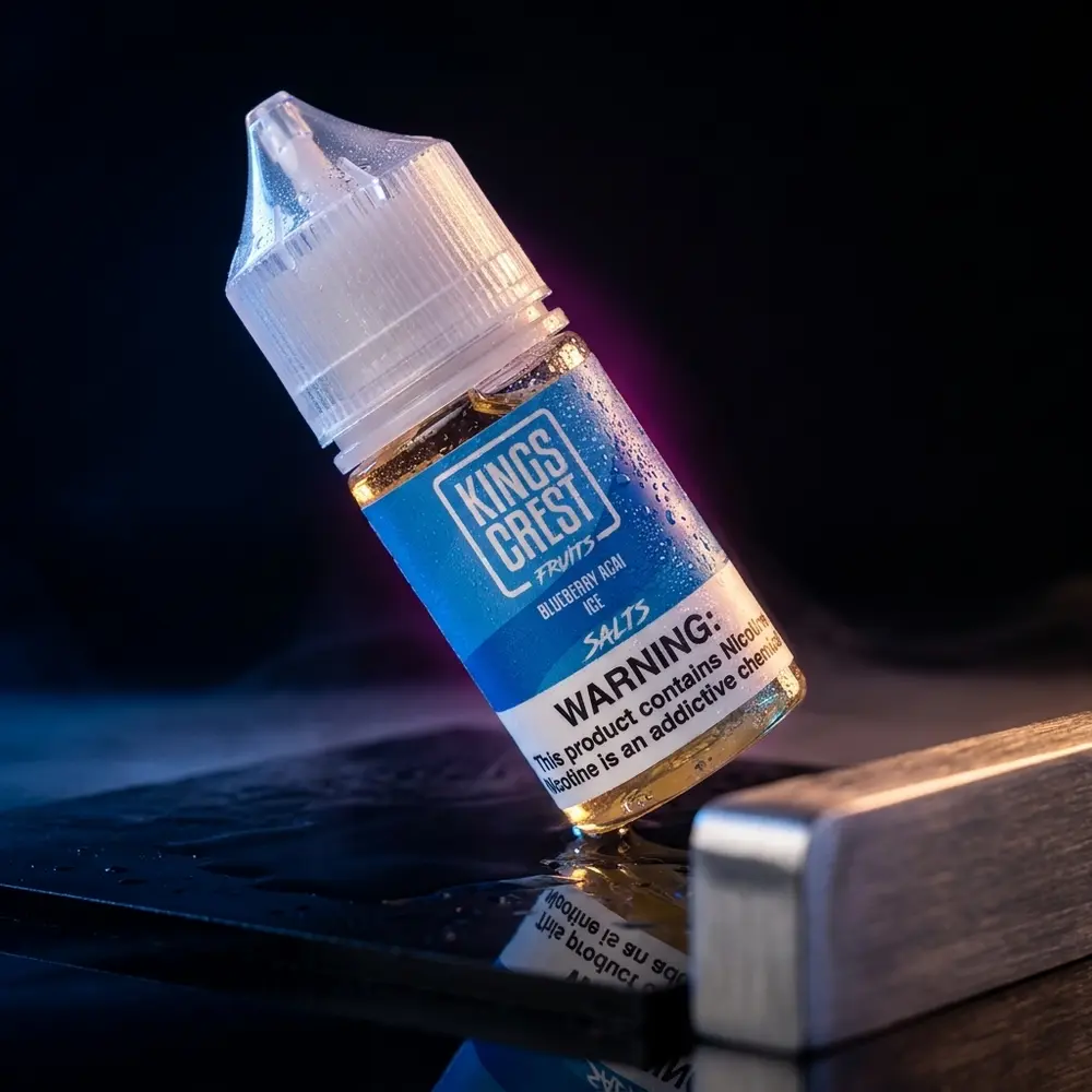 Garrafa de liquido Kings Crest Salt Blueberry Acai Ice inclinada sobre acrilico preto molhado com luzes azul e magenta - Vapor Gringo