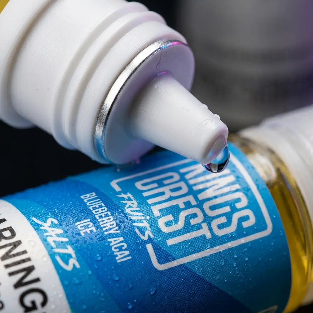 Macro do rotulo Kings Crest Salt Blueberry Acai Ice com gotas de condensacao e reflexo no bocal - Vapor Gringo