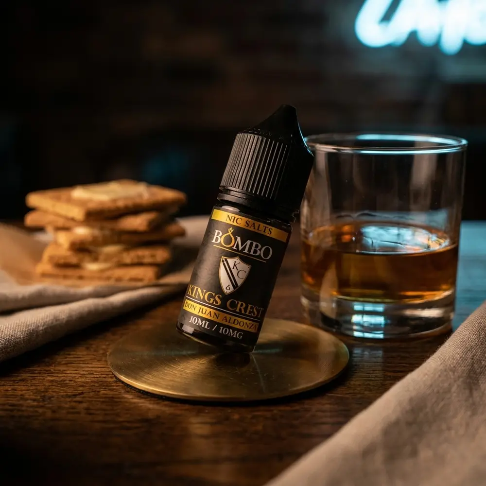 frasco don juan aldonza 30ml em lounge de luxo sobre mesa de carvalho ao lado de copo de whisky - Vapor Gringo