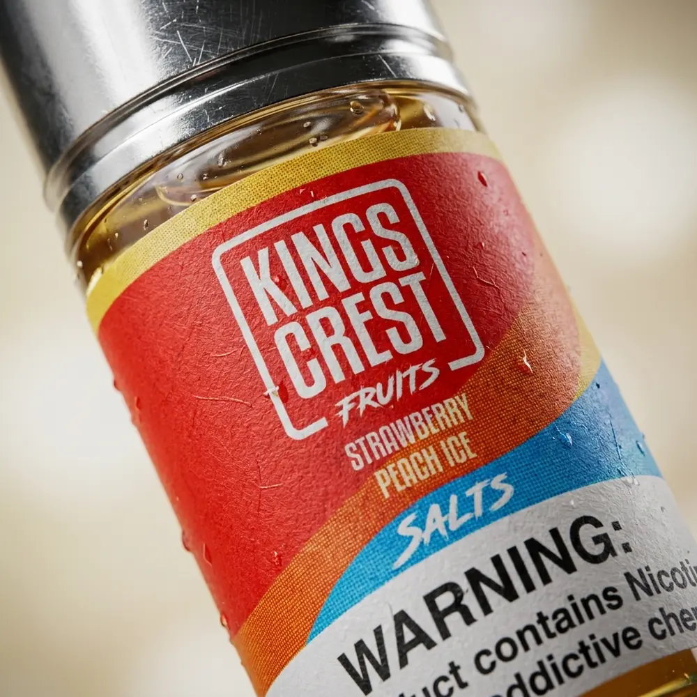 Close-up da etiqueta e bocal do líquido Kings Crest Salt com gotas de condensação e reflexos metálicos. - Vapor Gringo