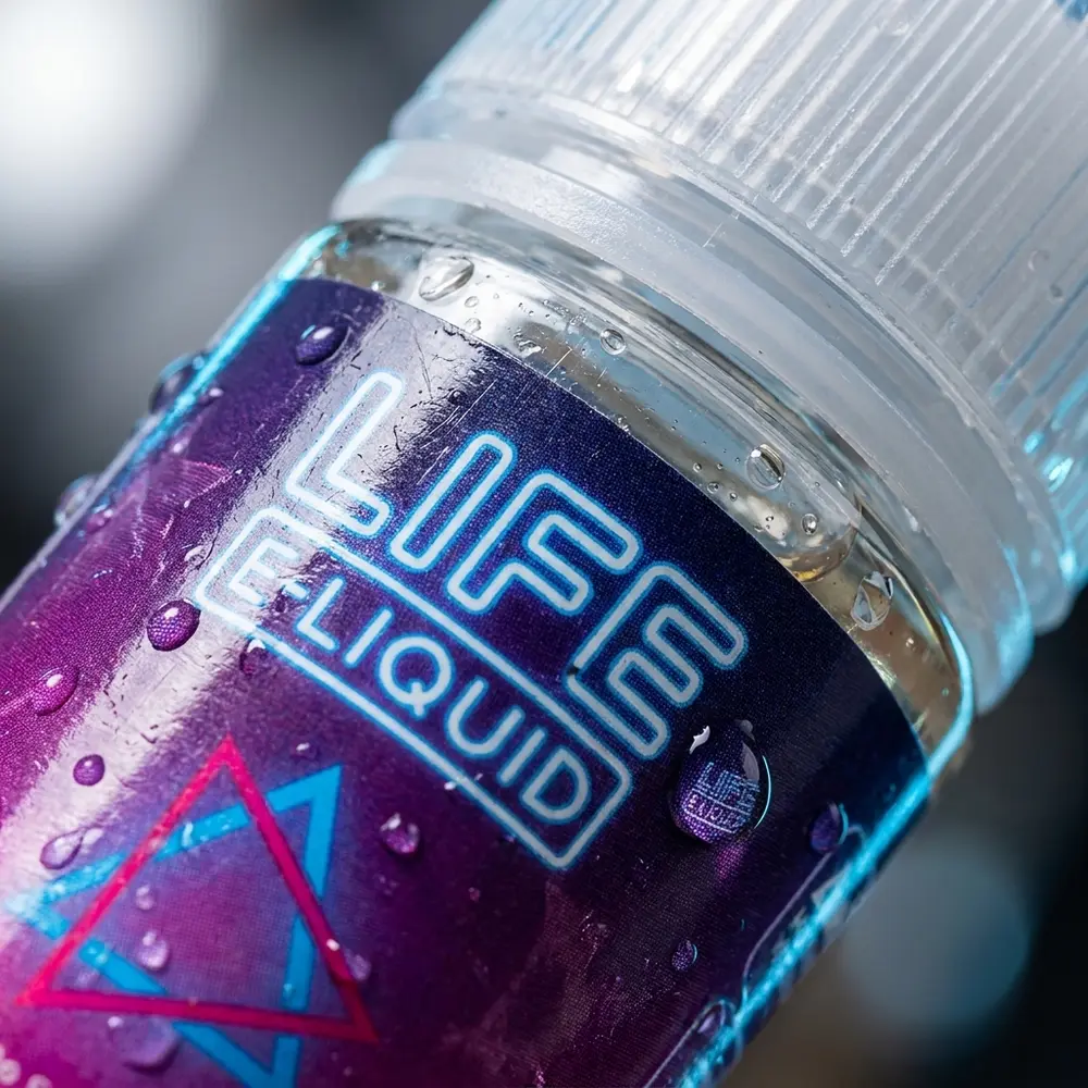 Detalhe do rótulo e bico da garrafa Liquido Life e-Liquid Salt - Winter com gotas de condensacao e reflexos - Vapor Gringo