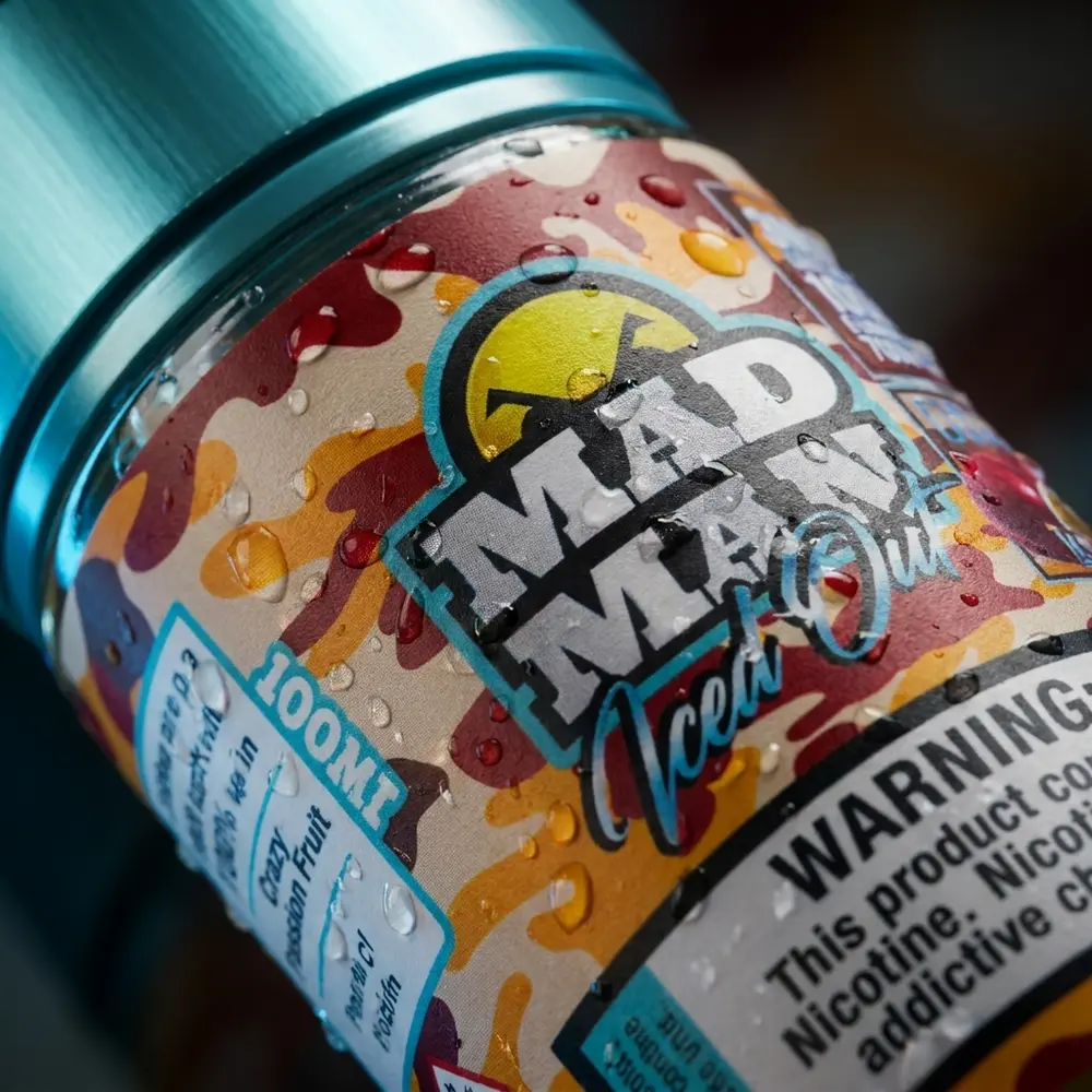 Close-up do rótulo do Liquido Mad Man Passion Fruit com gotas de água e reflexos metálicos - Vapor Gringo