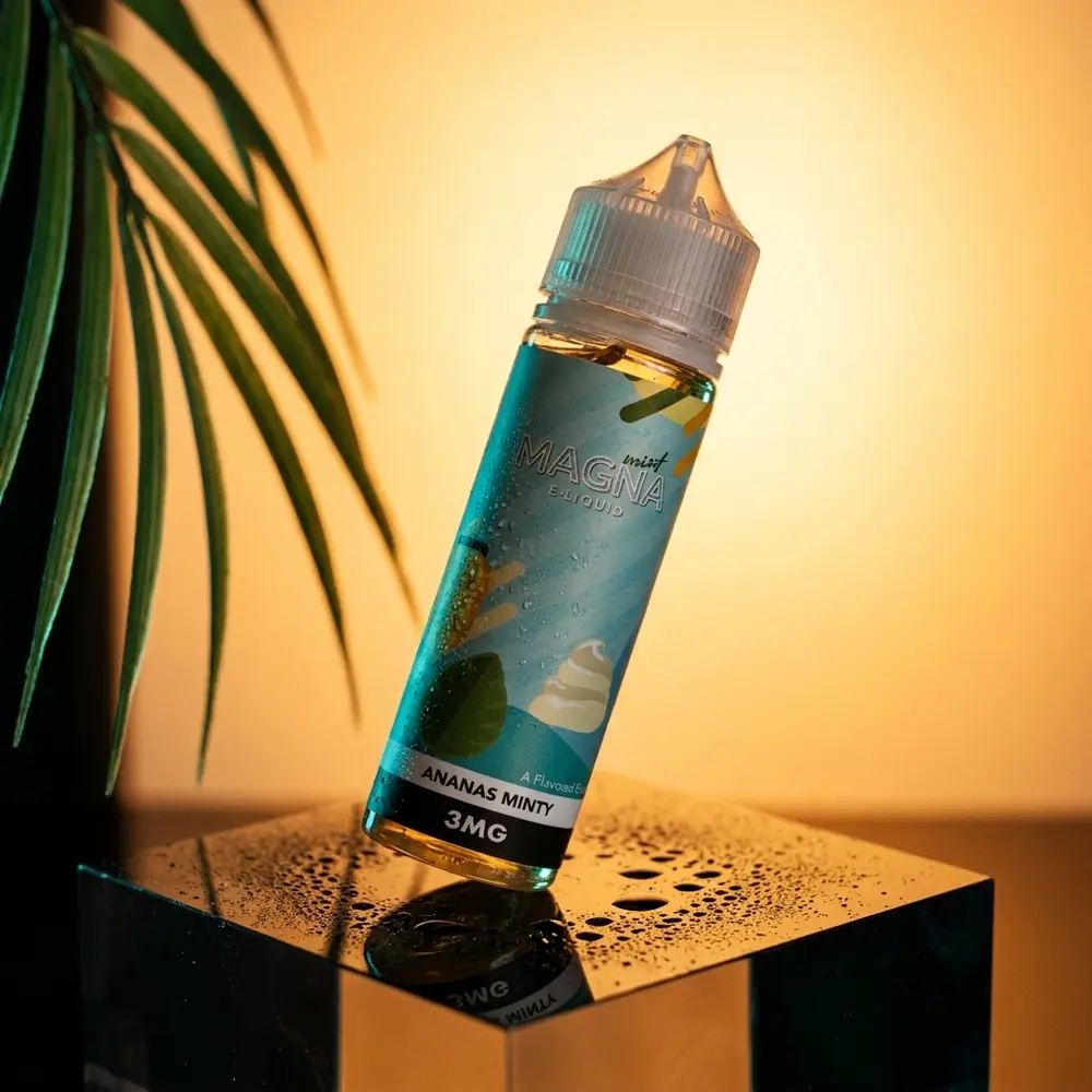 Garrafa do Líquido Magna Ananas Minty 60ml inclinada sobre acrílico preto com condensação e luzes âmbar e ciano - Vapor Gringo