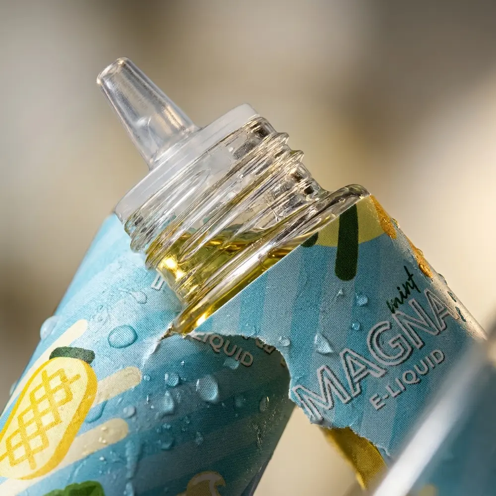 Close-up do bico e rótulo do Líquido Magna Ananas Minty mostrando gotas, textura do vidro e reflexos - Vapor Gringo