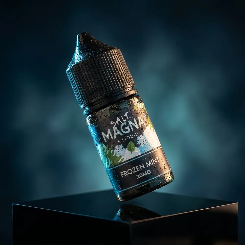 Garrafa do liquido Magna e-Liquid Salt Frozen Mint com gotas de condensacao sobre base preta e reflexos dramaticos - Vapor Gringo