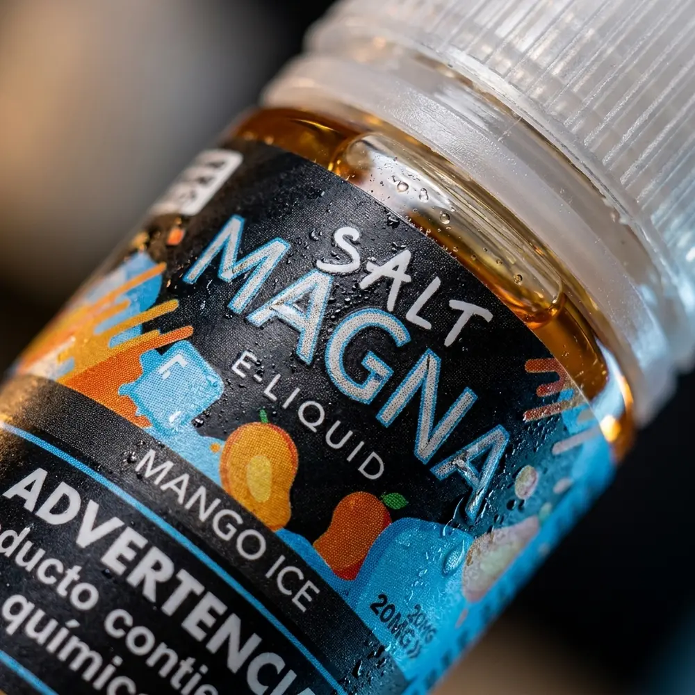 Close-up da etiqueta e bocal do Liquido Magna Mango Ice com gotas e textura detalhada da rotulagem - Vapor Gringo