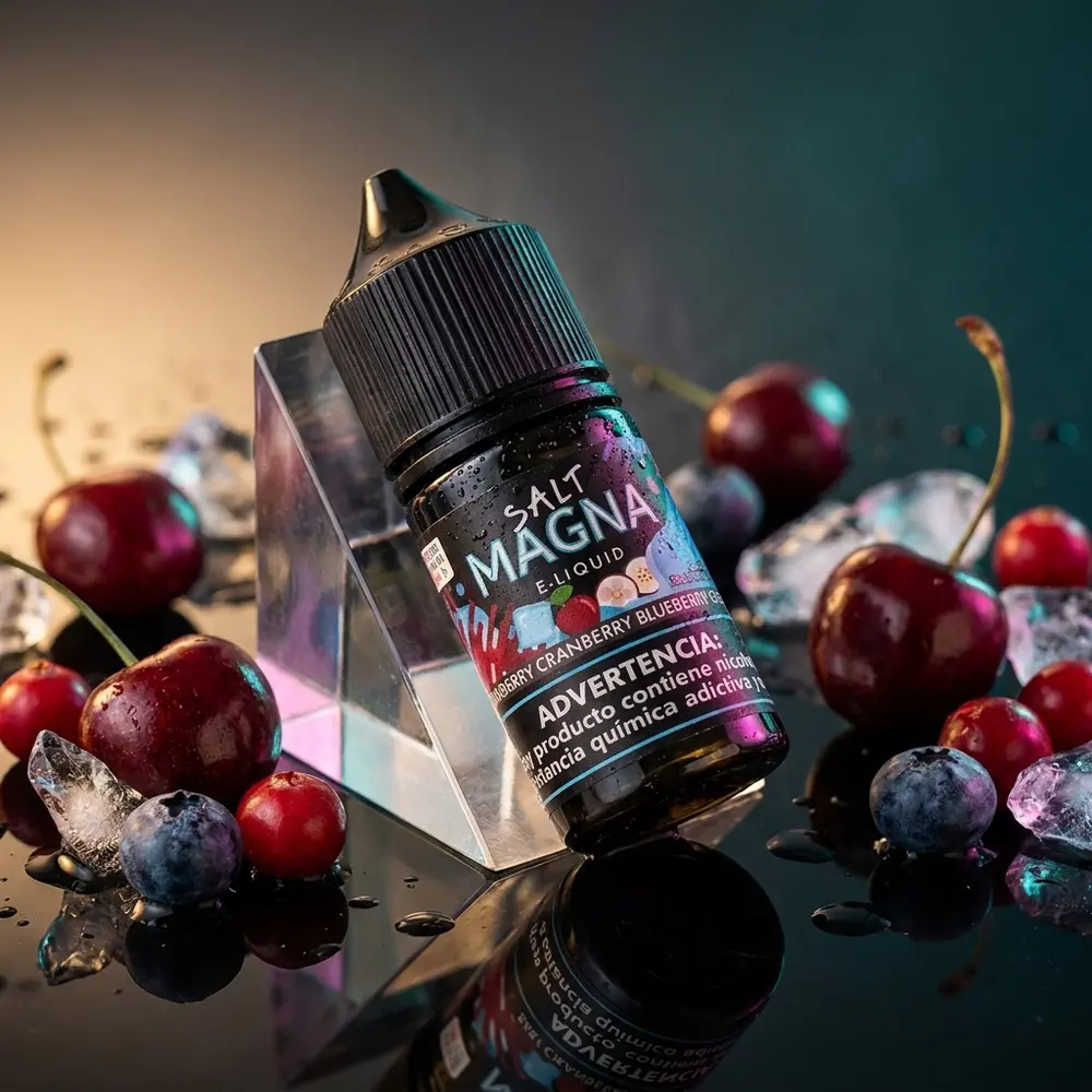 Frasco Liquido Magna Salt Cherry Cranberry Blueberry Ice inclinado sobre base acrilica preta com gelo e frutas ao redor - Vapor Gringo