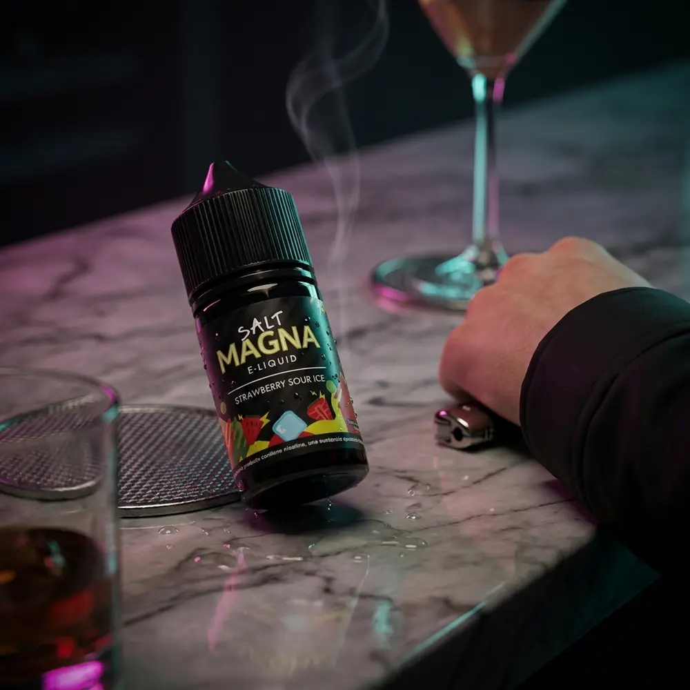 Líquido Magna Strawberry Sour Ice sobre balcão noturno com reflexos neon, copo desfocado e ambiente de luxo - Vapor Gringo