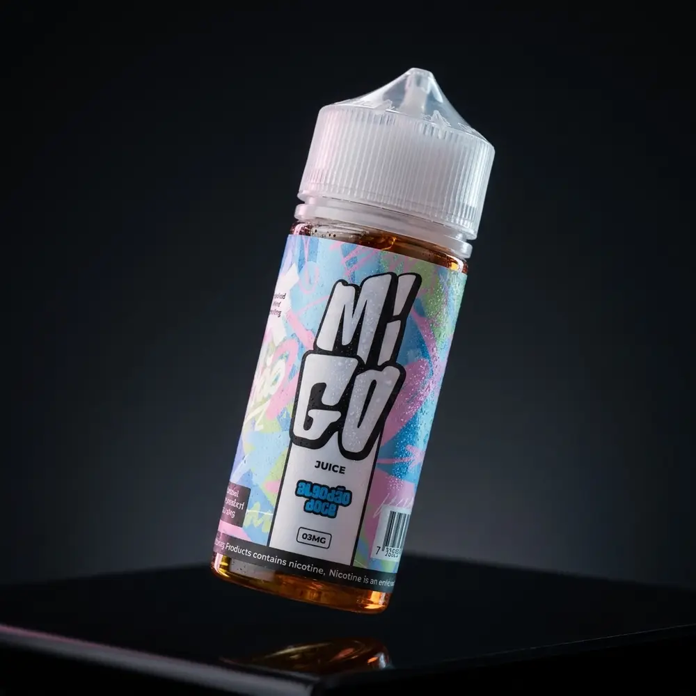 Líquido Migo Algodão Doce em close-up de estúdio escuro, frasco inclinado com luz rosa e reflexos premium - Vapor Gringo