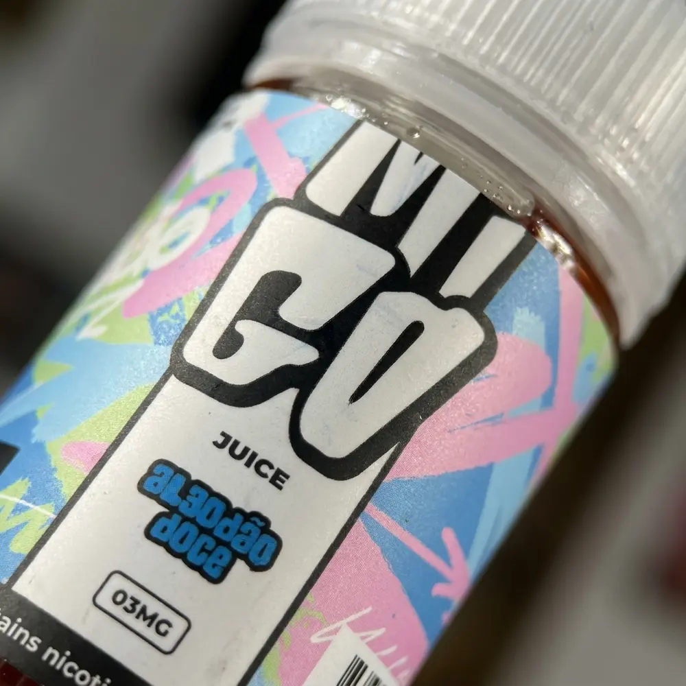 Detalhe do rótulo do Líquido Migo Algodão Doce, textura do rótulo, tipografia preservada e gotas de condensação - Vapor Gringo