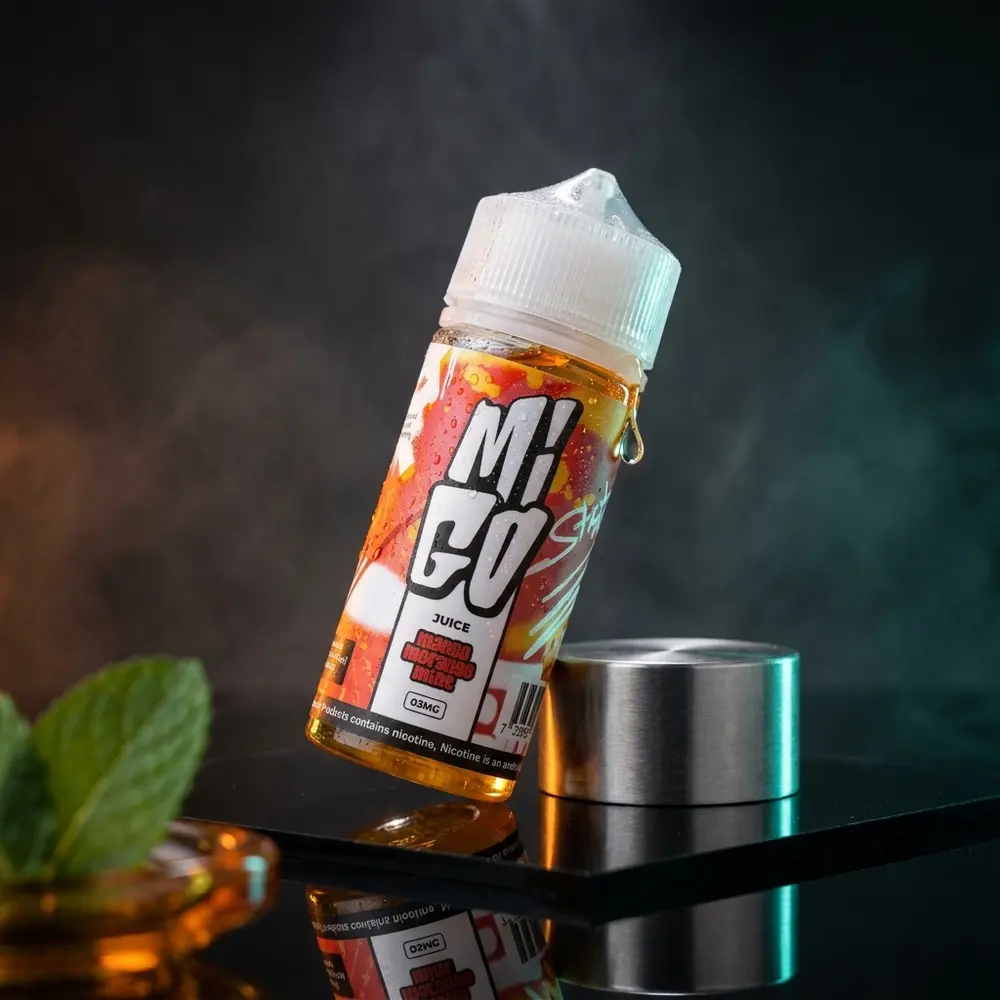 Frasco Liquido Migo Mango Morango Mint sobre acrilico escuro com condensacao e luzes laranja e verde - Vapor Gringo