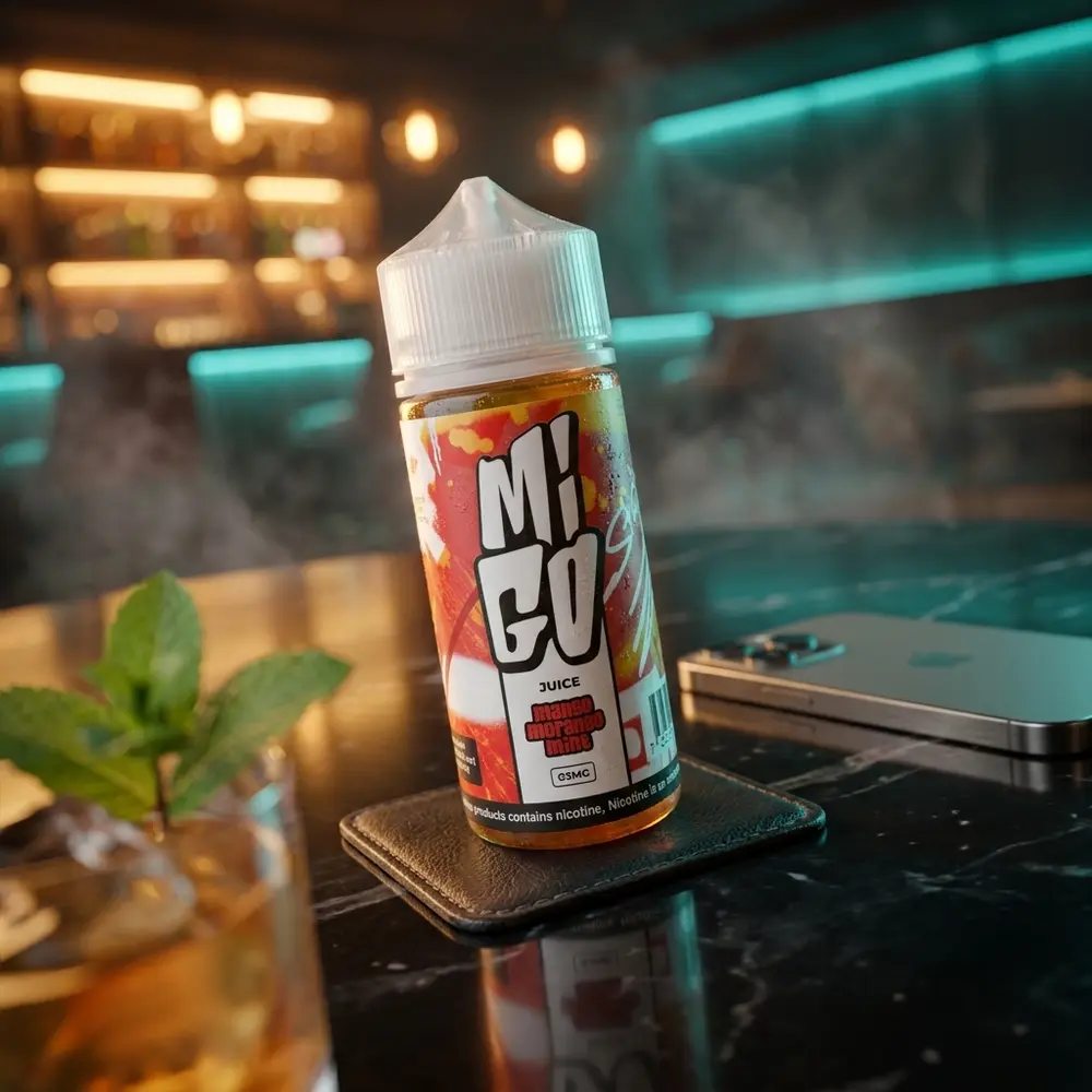 Frasco Liquido Migo Mango Morango Mint apoiado em descanso de couro sobre mesa de lounge com luzes ambar e verde - Vapor Gringo