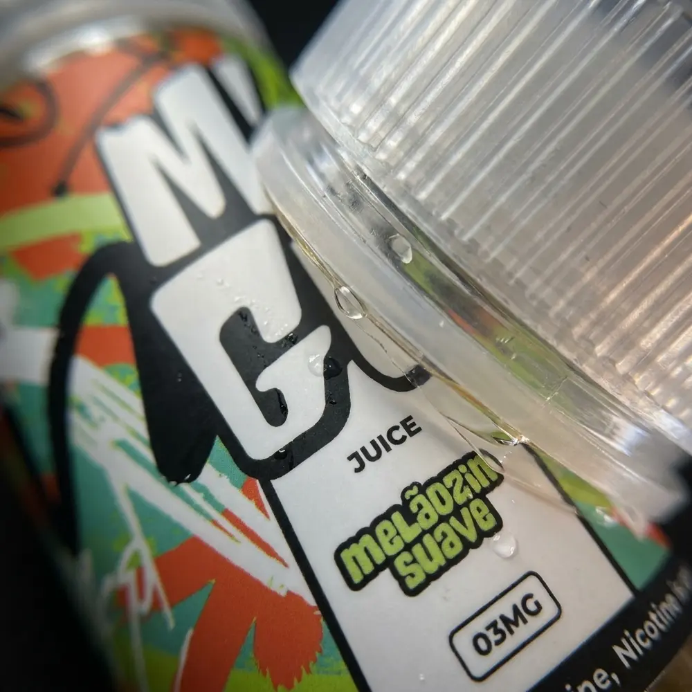 Close-up do rótulo Liquido Migo Melozin Suave 100ml mostrando tipografia, textura do vidro e gotas de condensação - Vapor Gringo