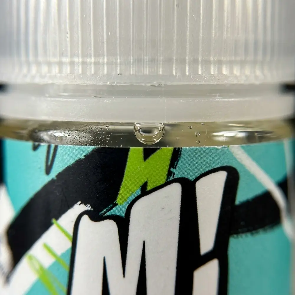 Macro do bico e rótulo do Liquido Migo Menthol Zero Grau com gotas de condensacao e textura detalhada do vidro - Vapor Gringo