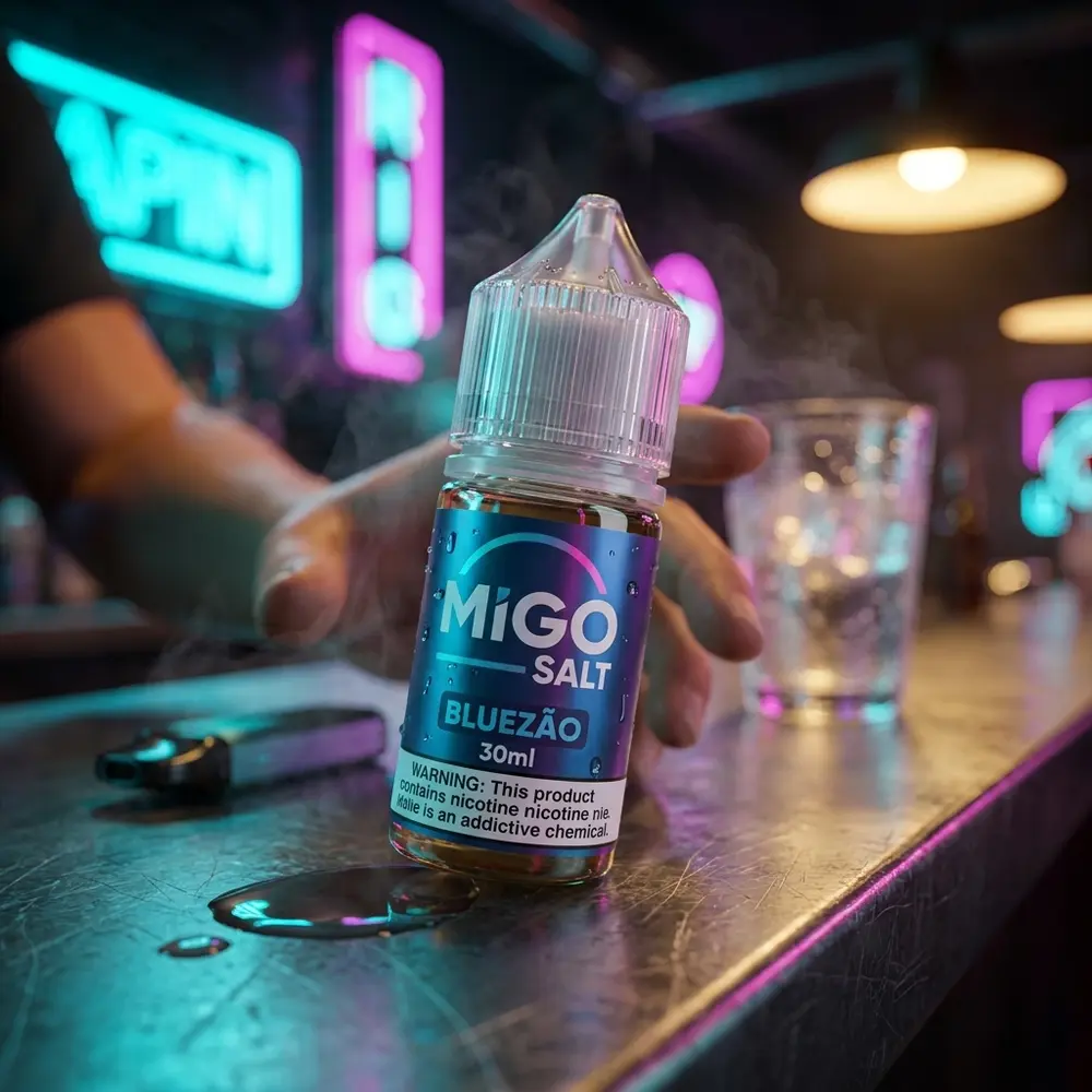 Líquido Migo Salt Bluezão apoiado em bancada urbana noturna com reflexos neon e mão em segundo plano - Vapor Gringo