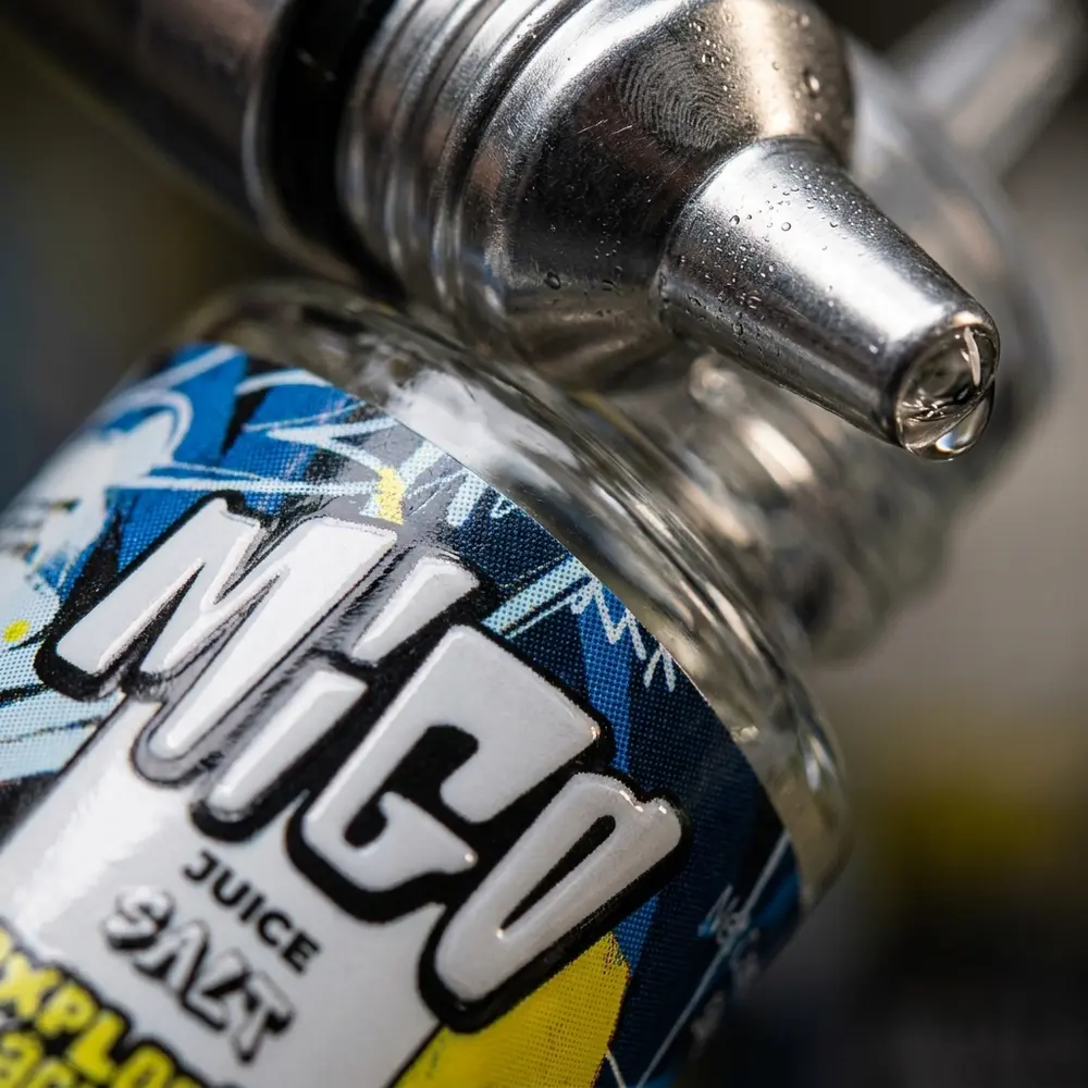 Plano detalhe do rótulo e do bico do frasco Migo Salt Explosão Ácida com gotas de condensação e micro-reflexos - Vapor Gringo