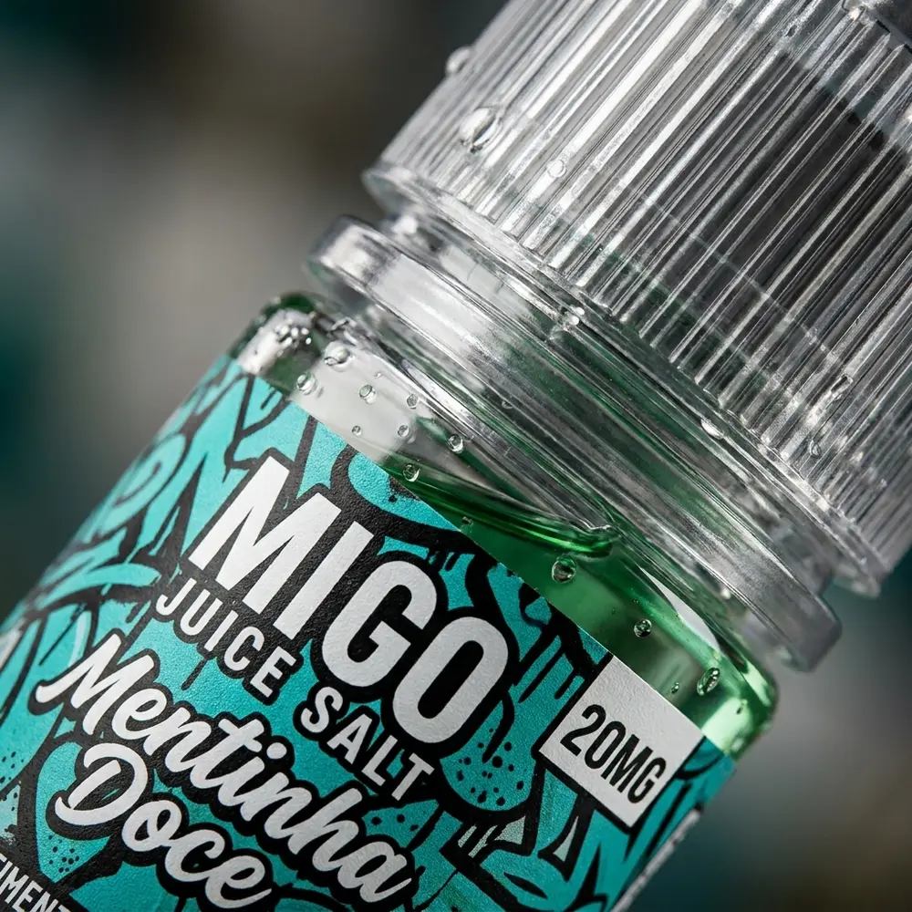 Close-up da etiqueta e bocal do Líquido Migo Salt Mentinha Doce com gotas de condensação e reflexos. - Vapor Gringo