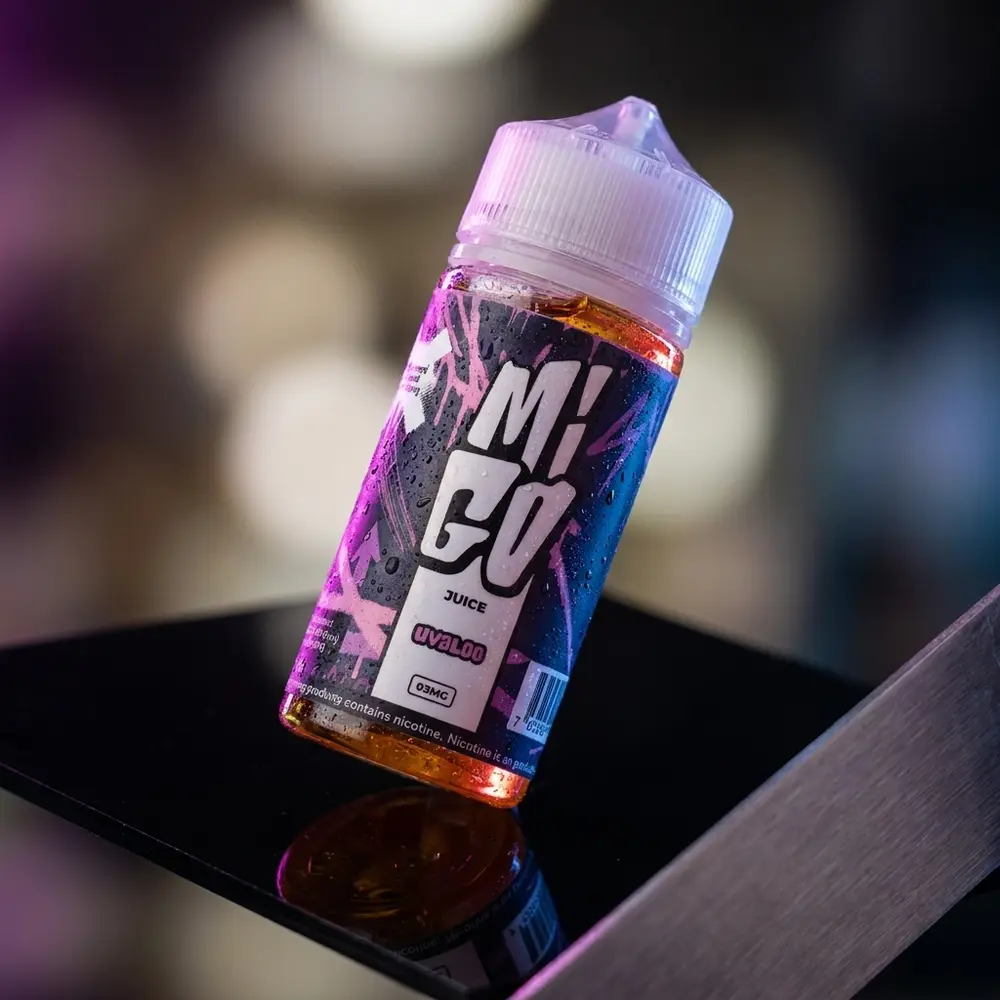 Garrafa Líquido Migo Uvaloo em close sobre acrílico preto com iluminação roxa e reflexos luxuosos - Vapor Gringo
