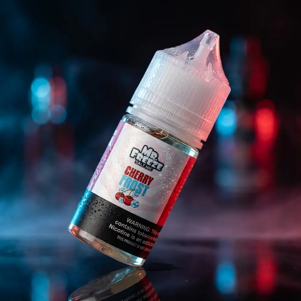 Frasco de liquido Mr. Freeze Salt Cherry Frost sobre base acrilica preta com condensacao e reflexos azul e vermelho - Vapor Gringo