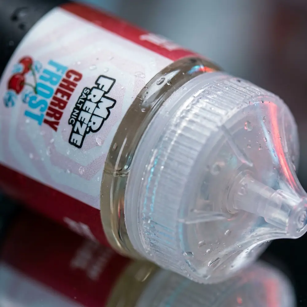 Close-up do rotulo e bico do liquido Mr. Freeze Cherry Frost com gotas de condensacao e textura brilhante - Vapor Gringo