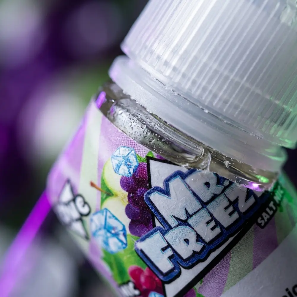Close-up do rótulo e bico do Liquido Mr. Freeze Salt com condensação e micro-reflexos roxo e verde - Vapor Gringo