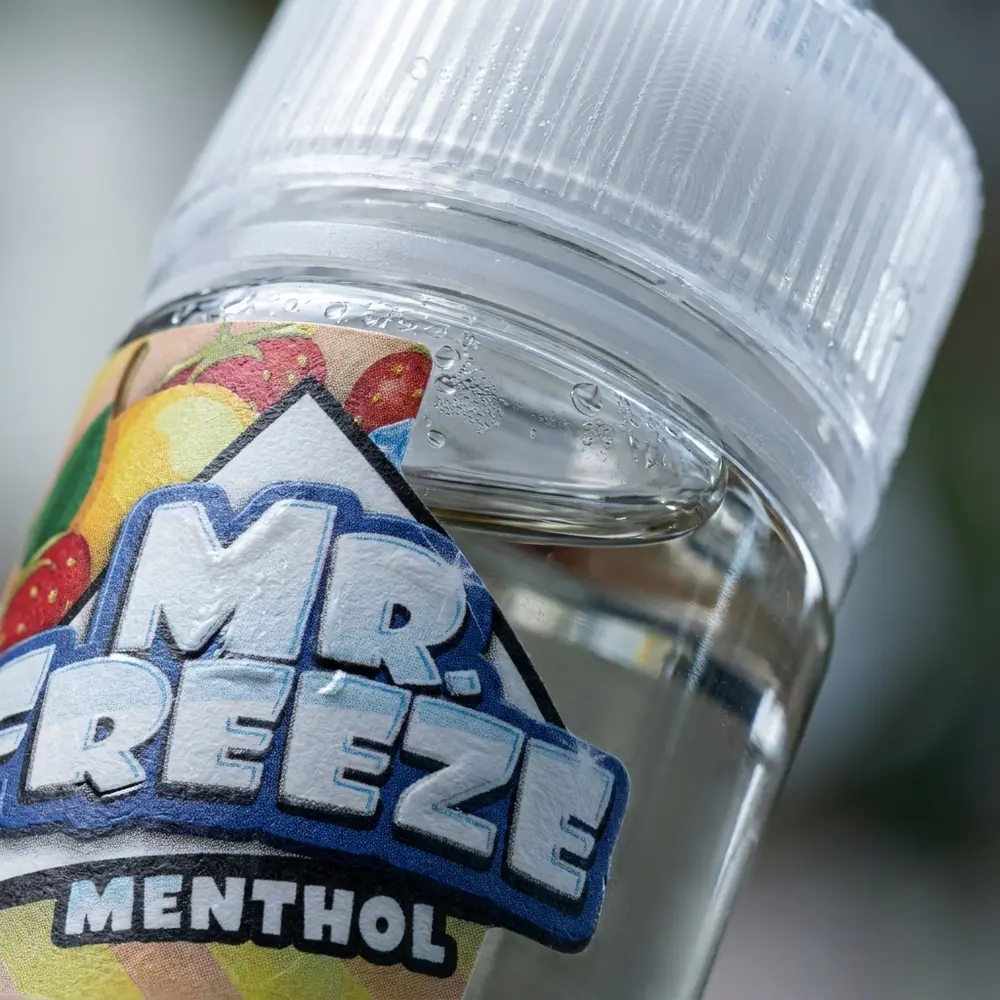 Close-up do rótulo e bico do Líquido Mr. Freeze Salt Strawberry Mango Frost com gotas, textura do vidro e reflexos - Vapor Gringo